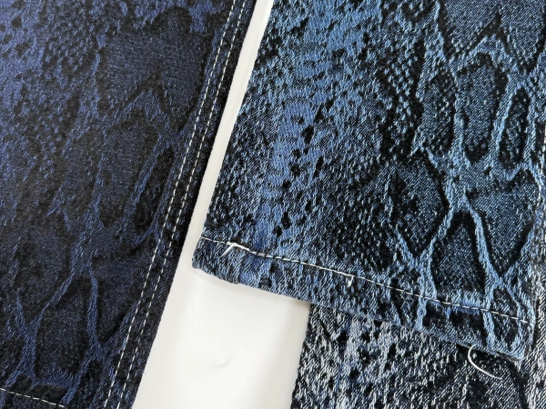 Close-up of reptile inspired chenille jacquard denim fabric with dimensional texture