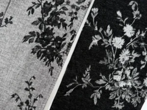 Close-up texture of black floral chenille jacquard denim fabric showing raised floral surface and denim base_